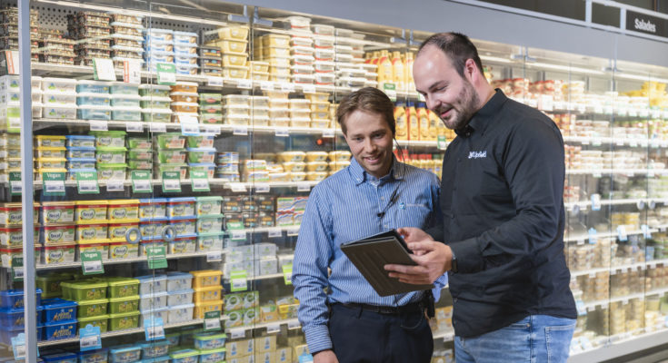 een vertegenwoordiger legt wat uit aan een Albert Heijn medewerker voor het boterschap