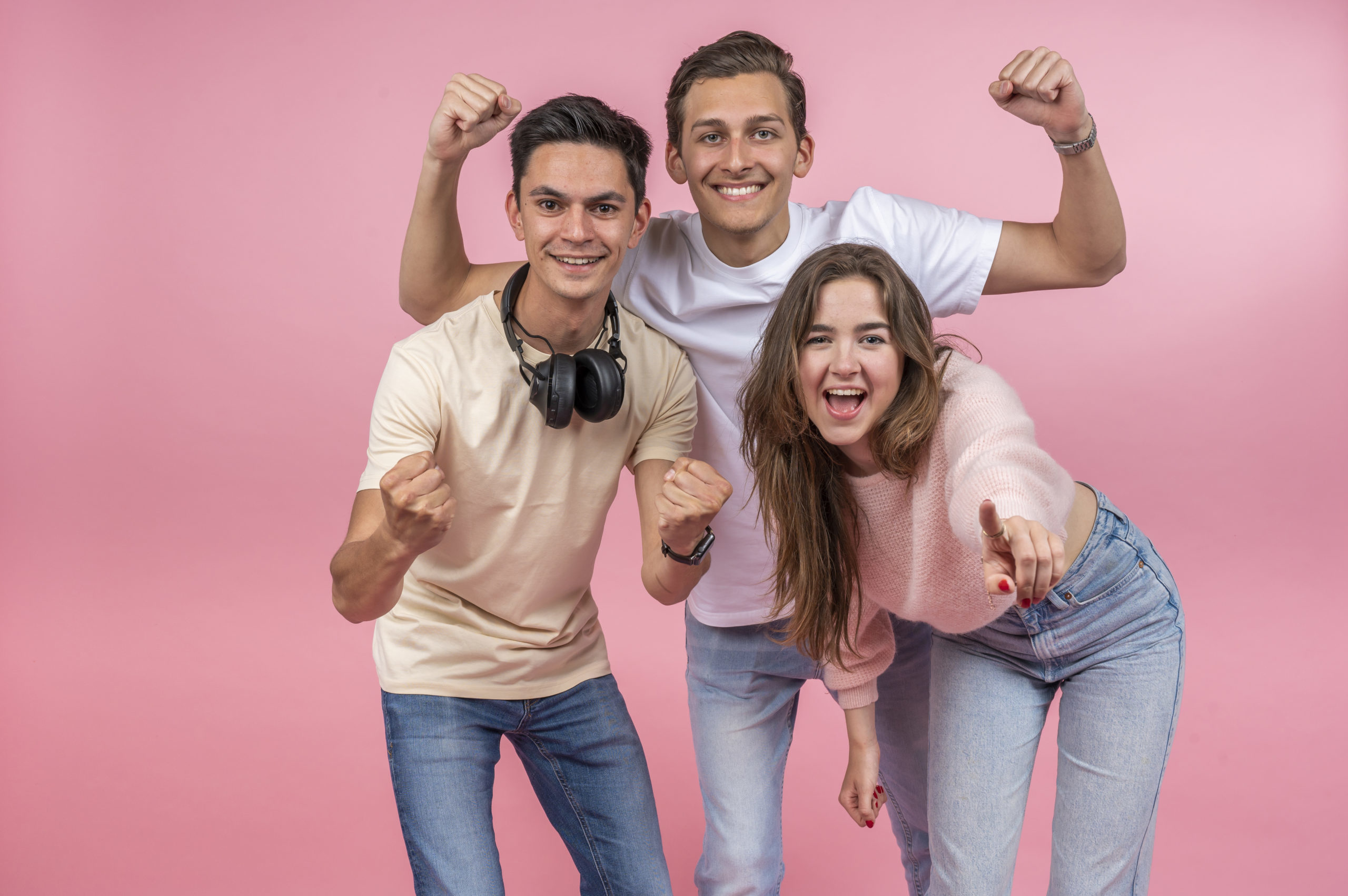 Een jongen met een JBL koptelefoon en nog een jongen en meisje juichen