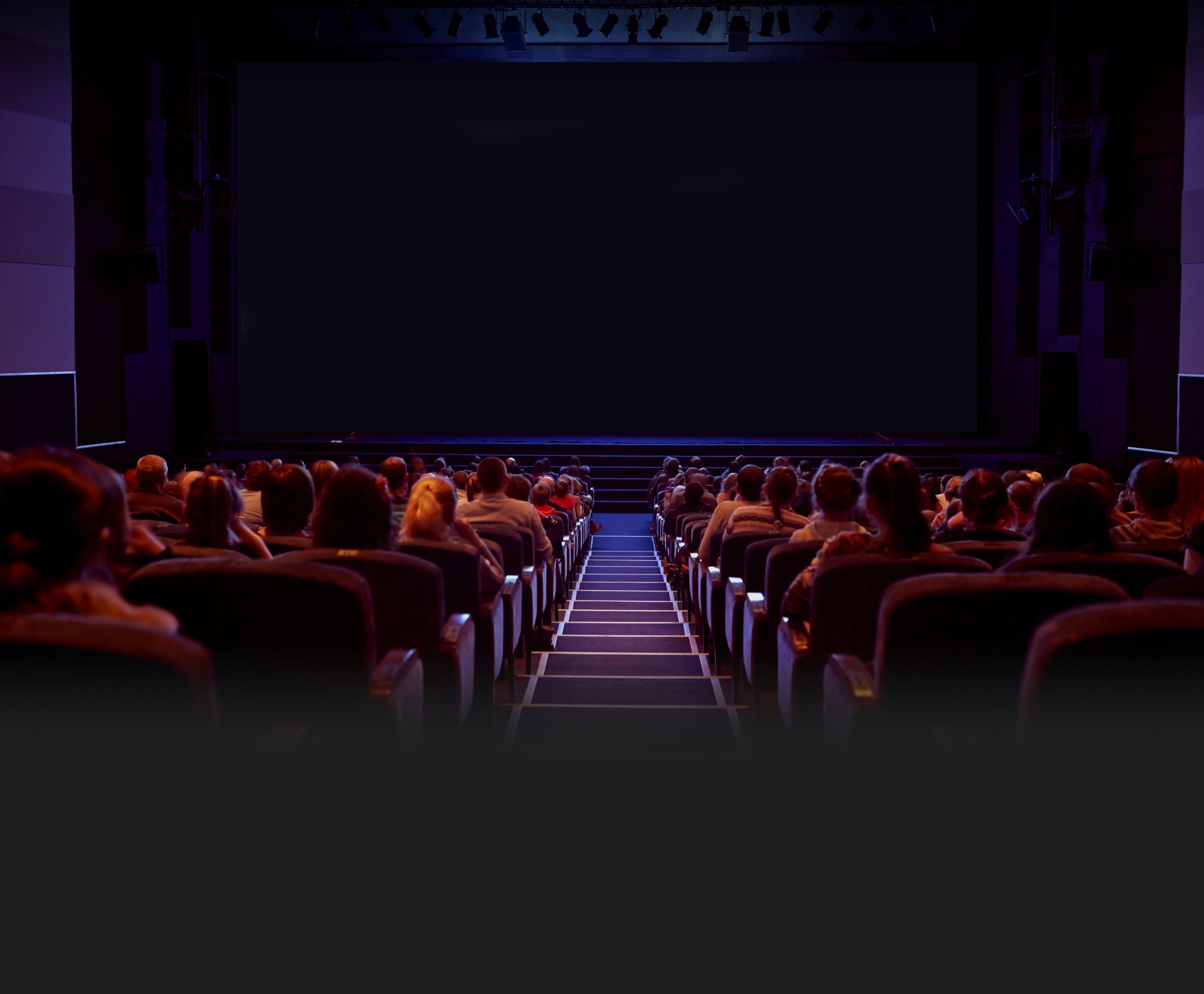 een donkere bioscoopzaal met veel publiek in de bioscoopstoelen