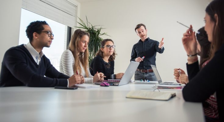 vijf sales vertegenwoordigers en junior rayonmanagers krijgen een fysieke training van een trainer in blauwe blouse