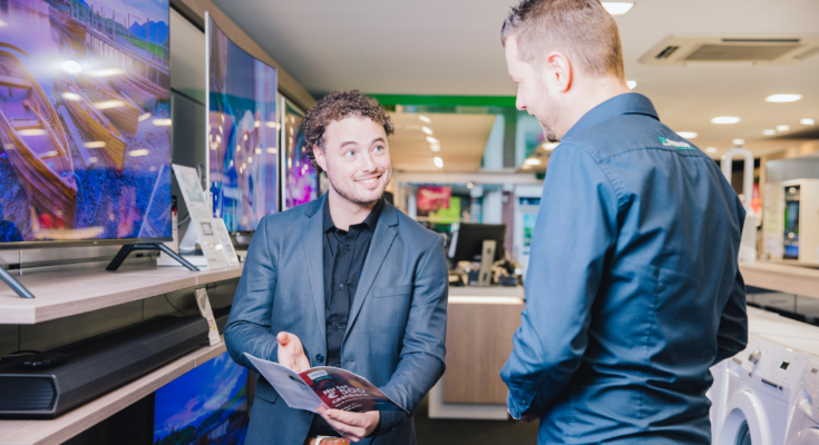 mannelijke verkoper met krullen vertelt klant over de televisies van Samsung in de MediaMarkt