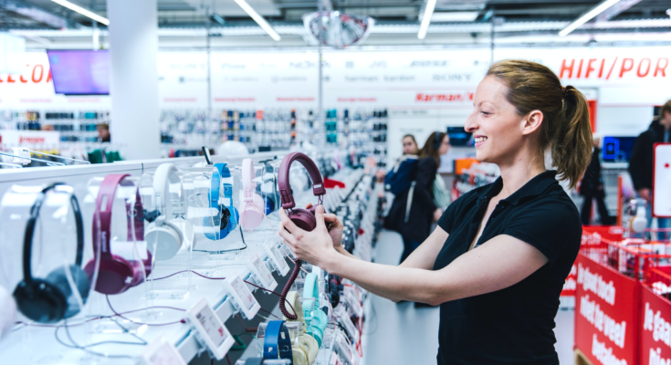 vrolijke vrouwelijke klant pakt een JBL koptelefoon op in de MediaMarkt